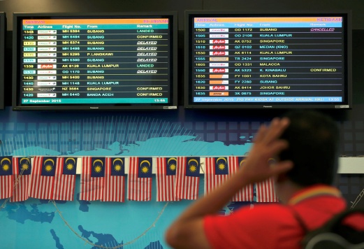 ORANG ramai melihat papan layar elektronik yang menunjukkan beberapa penerbangan di LTAPP terpaksa ditangguhkan akibat jerebu. FOTO Mikail Ong