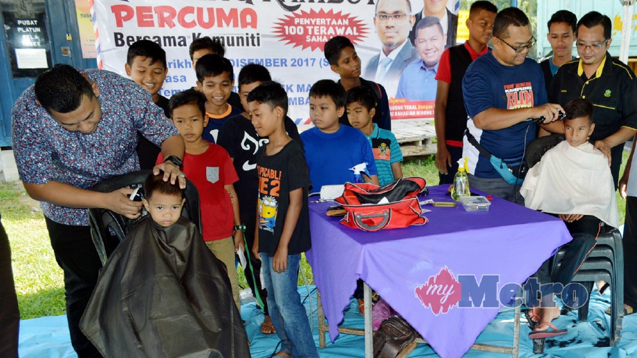 MOHD Norhiesham (kiri) melakukan simbolik menggunting rambut kanak-kanak sempena Program Gunting Rambut Percuma. FOTO Muhammad Shalaby Shahbuddin
