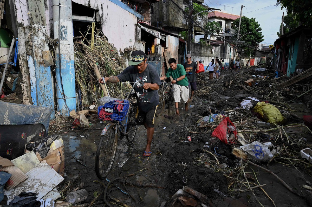 PENDUDUK melalui laluan yang dipenuhi sisa dan kerosakan akibat ribut Nalgae di Noveleta, Cavite. FOTO AFP