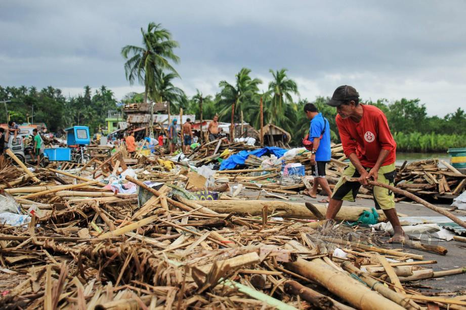PENDUDUK membersihkan bekas Taufan Kammuri di Filipina.
