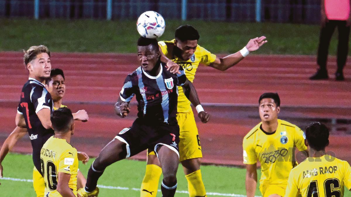 PEMAIN Kuching City FC (jersi hitam) berebut bola dengan pemain Penang FC pada perlawanan di Stadium Negeri, malam tadi. FOTO Bernama 