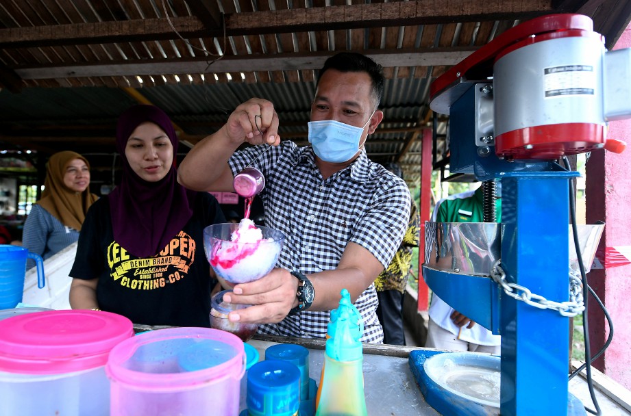 MOHD Sharim kanan) mencuba membuat ais batu campur ketika beramah mesra dengan para penduduk setempat pada kempen di Bandar Dara Felda Chini, semalam. FOTO Bernama 