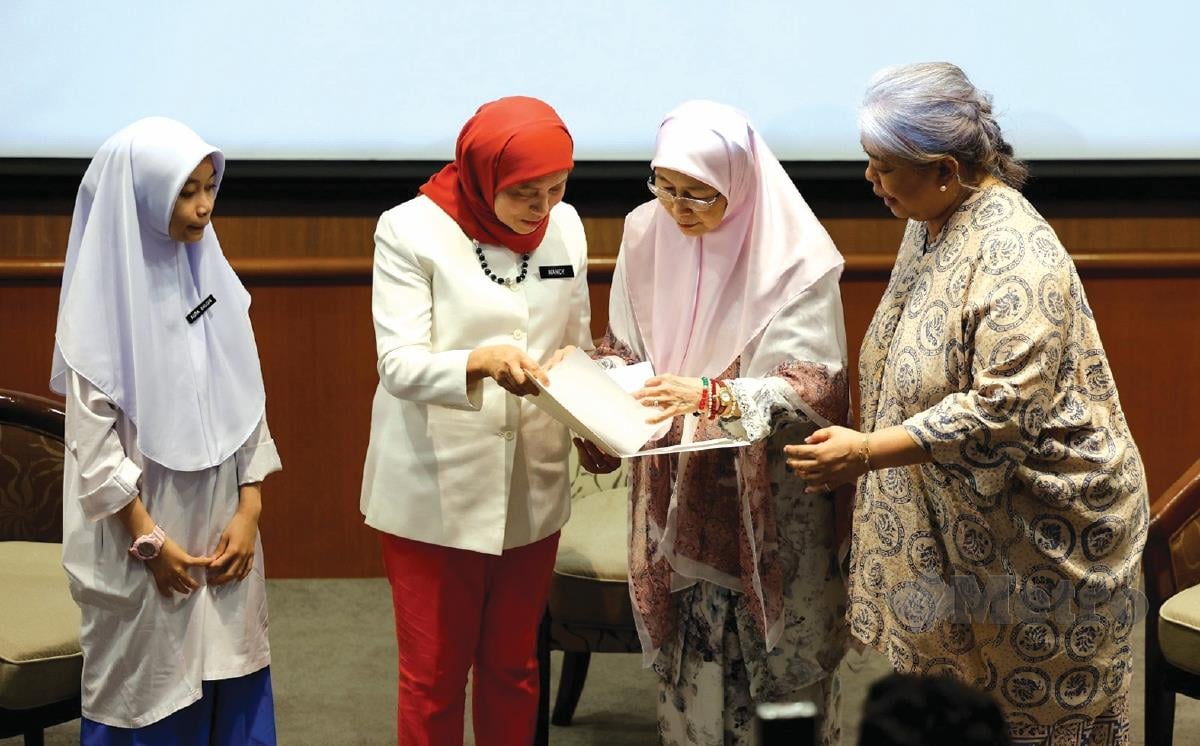 WAN Azizah (dua dari kanan) bersama Nancy (dua dari kiri) dan Dr Hartini (kanan) melihat memorandum kerjasama antara kementerian bersama badan bukan kerajaan (NGO) yang disampaikan pelajar, Aura Balqis ketika program Town Hall Perlindungan Kanak-Kanak di Era Digital di Universiti HELP, Kuala Lumpur.