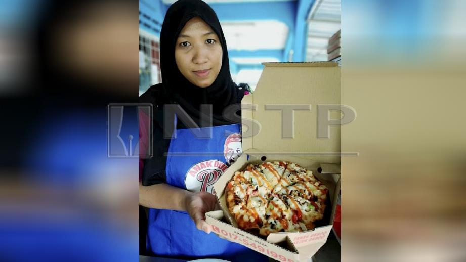 Nor Rosidah menunjukkan piza yang siap ditempah. FOTO Roselan Ab Malek