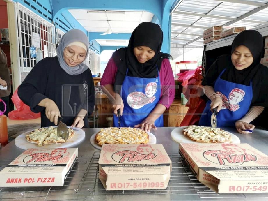 Nor Rosidah (tengah) bersama pekerjanya menyiapkan piza sambal hitam dan sambal petai yang ditempah pelanggan. FOTO Roselan Ab Malek