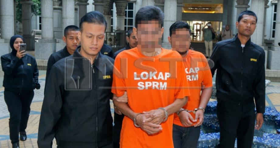 ANGGOTA SPRM mengiring dua  lelaki yang menyamar sebagai pegawai kementerian di Mahkamah Majistret Putrajaya. FOTO Luqman Hakim Zubir