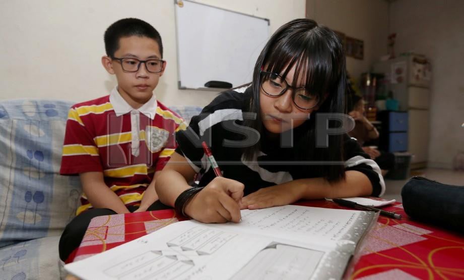 POR Hui Ling, 11, dari Taman Desa Jaya Kampung Gong Pak Damak menunjukkan kemahirannya menulis jawi sambil diperhatiakn abangnya Por Jie Hao, 14. FOTO Imran Makhzan
