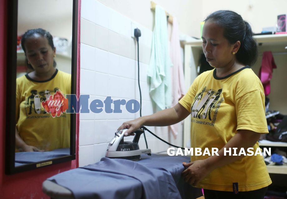 Pembantu rumah warga Indonesia, Posi R Shidin menggosok pakaian majikannya di Ampang. FOTO arkib NSTP