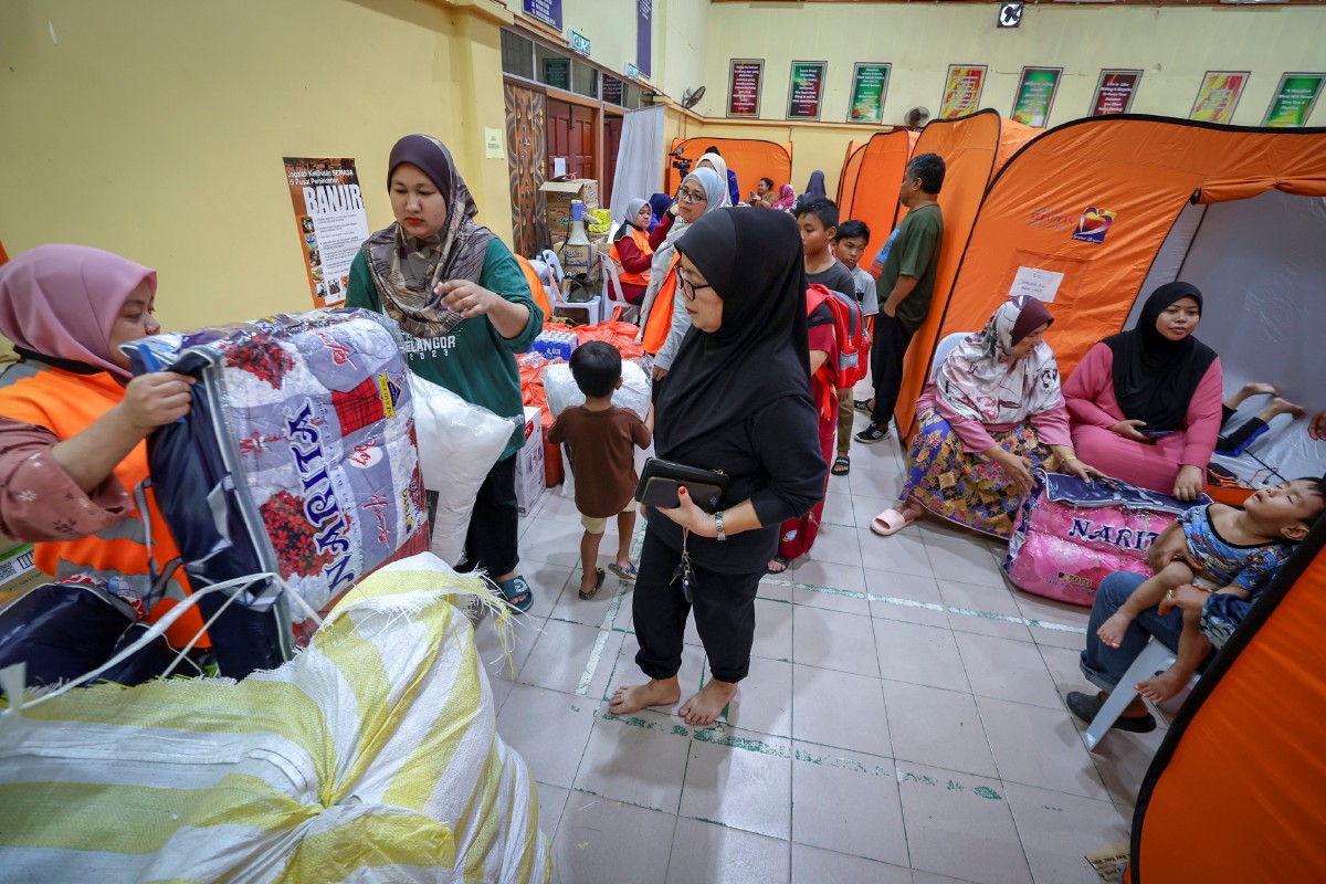 PETUGAS Jabatan Kebajikan Masyarakat mengagihkan barang keperluan kepada mangsa banjir. FOTO Bernama 