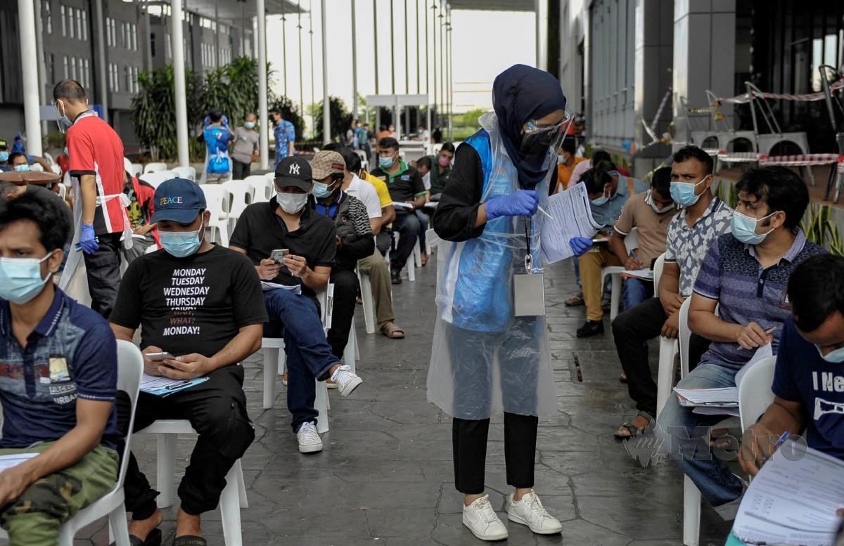 Sukarelawan membantu sebahagian pekerja warga asing mengisi borang pendaftaran untuk melakukan suntikan vaksin ketika hadir di PPV Pusat Konvensyen Bangi Avenue (BACC) di Bangi. FOTO AIZUDDIN SAAD
