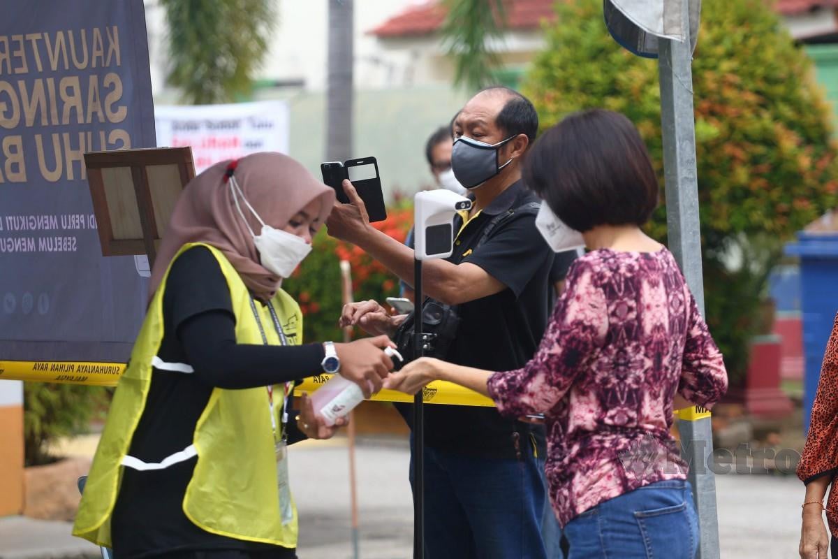 PETUGAS SPR menguruskan SOP dengan mewajibkan imbasan MySejahtera dan menggunakan sanitasi kepada pengundi di Pusat Mengundi SJK (T) Melaka Kubu, Melaka. FOTO Syafeeq Ahmad