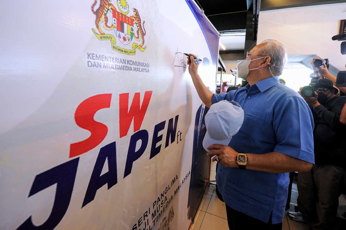 ANNUAR menandatangani kain rentang simbolik merasmikan Program Komuniti Keluarga Malaysia di Warung Pak Belalang di Kota Samarahan, hari ini. FOTO Bernama