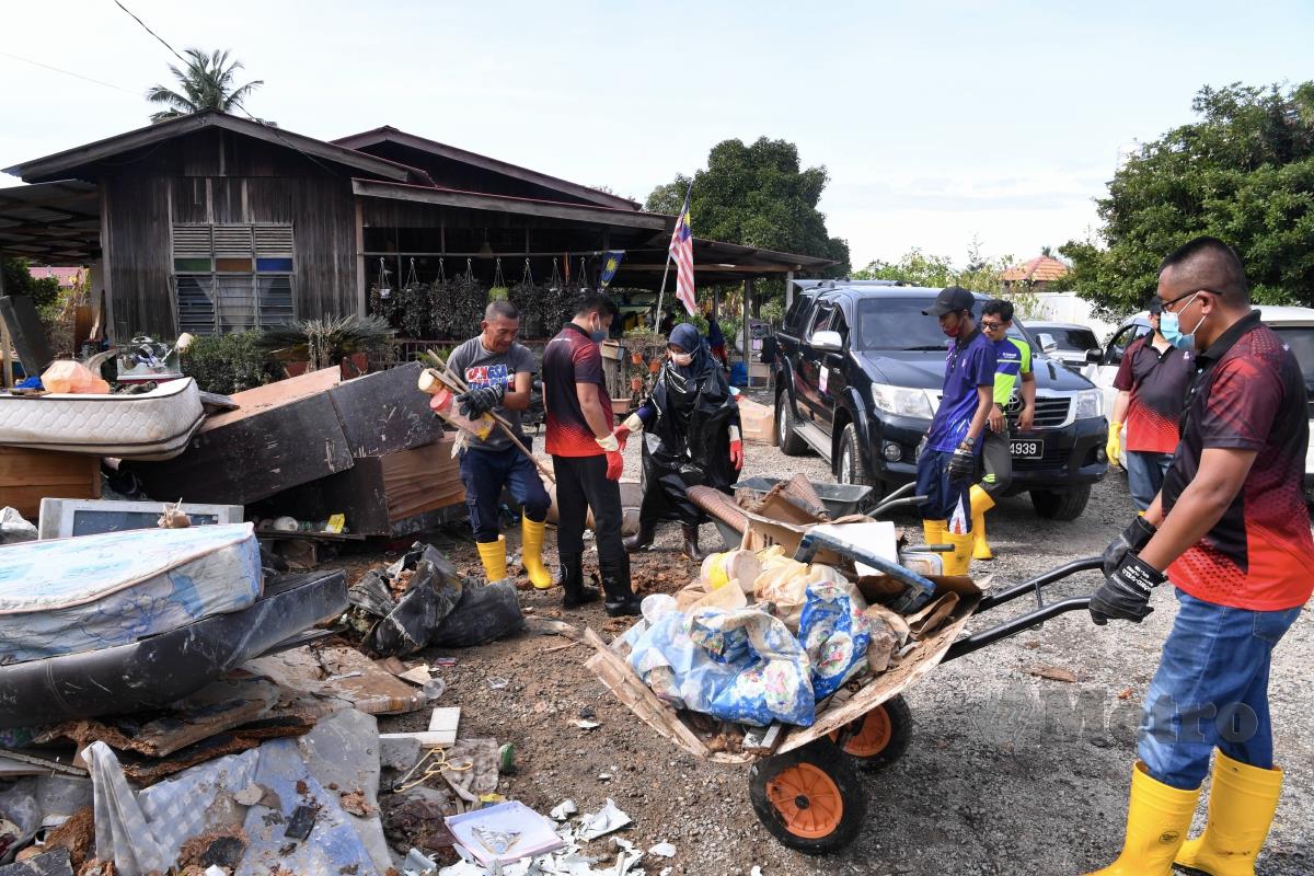 KAKITANGAN Yayasan Pelajaran Mara bergotong-royong membersihkan rumah penduduk di Kampung Bukit Changgang, baru-baru ini. FOTO Bernama 