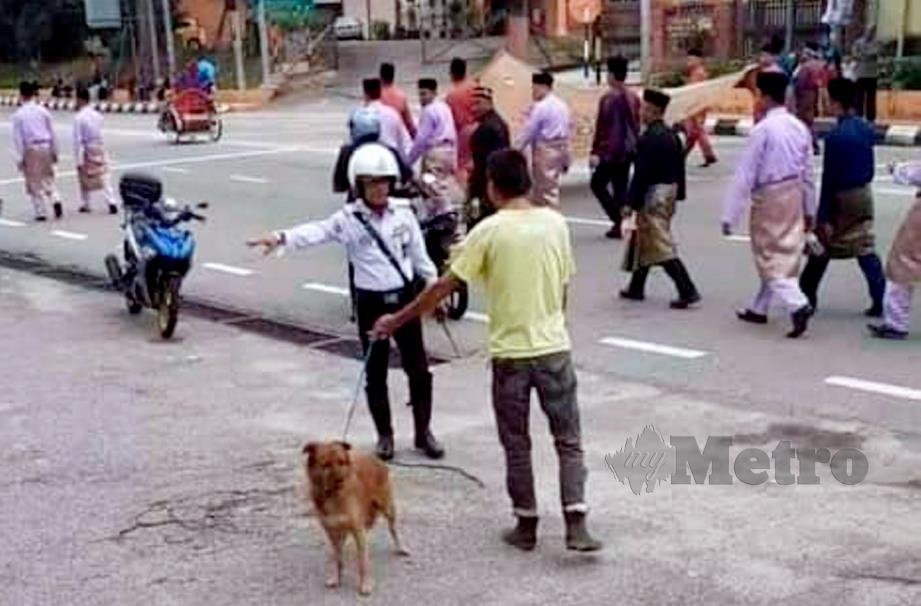 GAMBAR polis trafik menegur lelaki membawa anjing berdekatan lokasi peserta perarakan Maulidur Rasul tular di media sosial, hari ini. FOTO ihsan pembaca. 