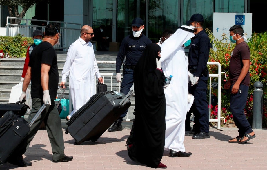 POLIS Qatar berdiri di hadapan hotel di Doha dan pelancong memakai penutup hidung dan mulut berikutan kebimbangan koronavirus. FOTO AFP.