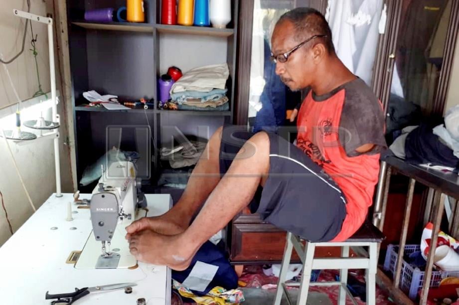 RAHIM menggunakan kedua-dua kakinya untuk menjahit dan mampu menyiapkan sepasang baju Melayu dalam tempoh sehari ketika ditemui di kedainya di Pulai Chondong, Machang. FOTO Sharifah Mahsinah Abdullah.