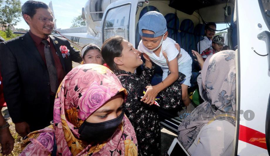 RAMAN (kiri) menyambut ketibaan tiga pesakit kanak-kanak yang diberi peluang menaiki helikopter. FOTO Malai Rosmah Tuah  