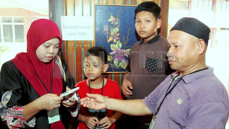 RAMLI (kanan) bersama Siti Azlina serta dua anaknya, Muhammad Amirul Hisham (dua kanan) dan Muhammad Amirul Hakim berkomunikasi dengan menggunakan telefon bimbit. FOTO Nik Abdullah Nik Omar