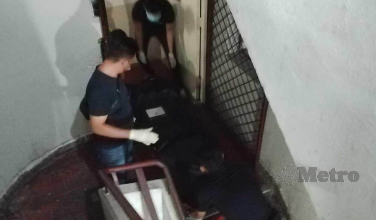 ANGGOTA polis mengangkat mayat mangsa yang ditemui terbaring di atas tilam bilik sewanya di Kampung Air, Kota Kinabalu. FOTO Juwan Riduan