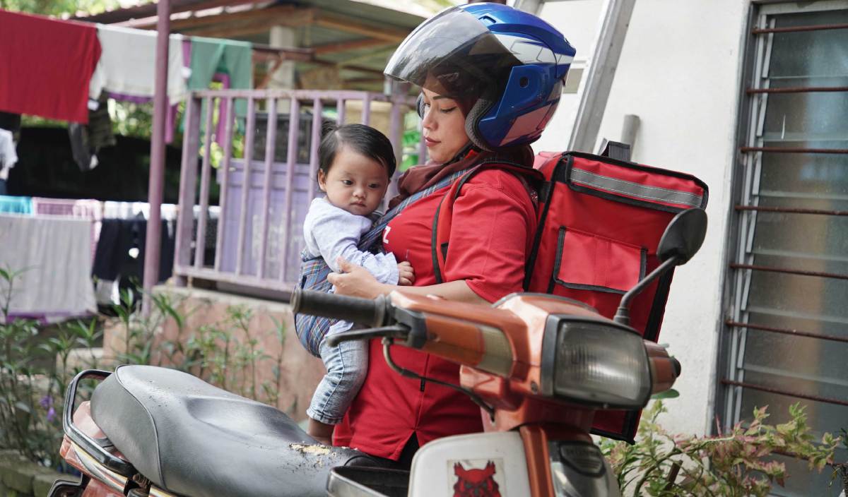 SITI Farah Hanim membawa anaknya, Siti Nur Ummairrah menaiki motor ke rumah pengasuh sebelum memulakan tugasan sebagai penghantar makanan dan barangan di sekitar Batang Kali. FOTO Nur Adibah Ahmad Izam