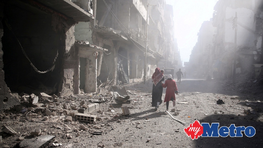 PENDUDUK berjalan sebelah bangunan yang rosak akibat serangan udara di Douma, Damascus, Syria. FOTO Reuters