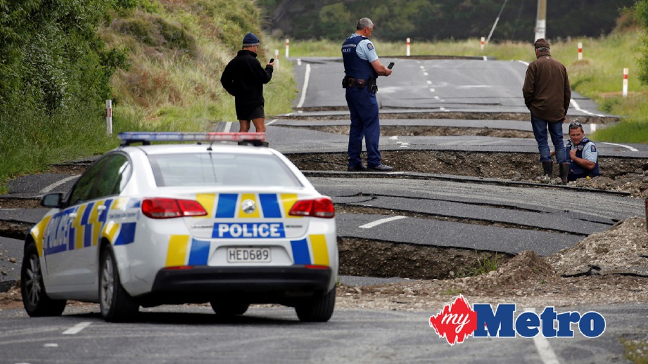 ANGGOTA polis dan penduduk tempatan melihat kerosakan jalan raya berhampiran Blenheim, New Zealand selepas gempa bumi. FOTO Reuters