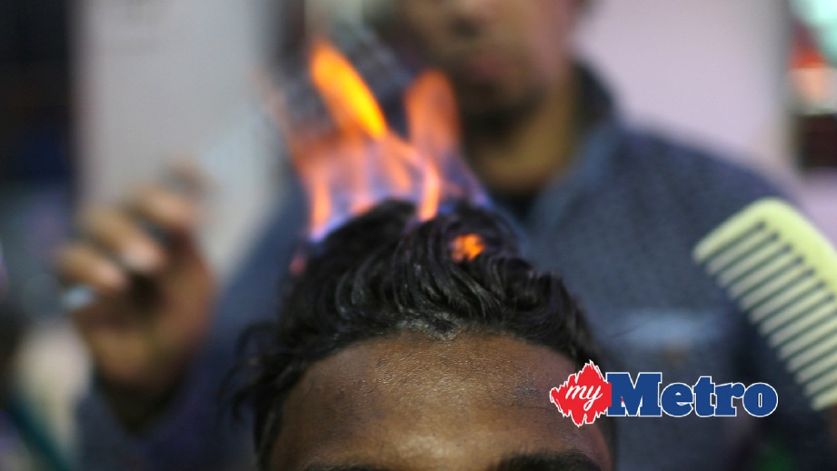 RAMADAN Odwan menyembur api untuk meluruskan rambut pelanggannya. FOTO Reuters