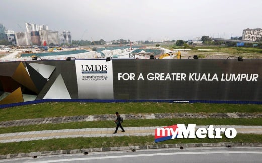 LELAKI berjalan di hadapan projek pembangunan Tun Razak Exchange di Kuala Lumpur. FOTO Reuters.