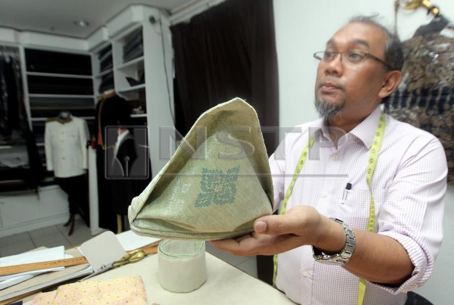 RUSHDI menunjukkan contoh tengkolok istiadat yang biasa dipakai Sultan Pahang dibuat daripada kain songket lapan tenunan khas ketika ditemui di butiknya di Jalan Besar, Kuantan, hari ini. FOTO Muhd Asyraf Sawal.