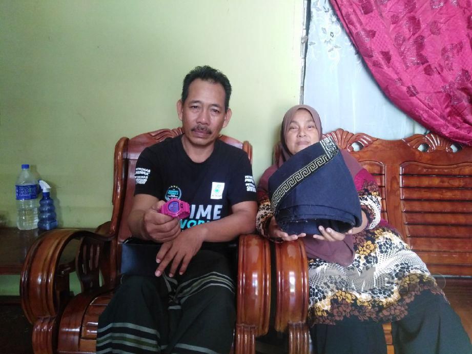 AZLAN dan Siti Hajar menunjukkan tengkolok dan jam tangan milik Mohd Azwan yang maut selepas traktor dipandunya terbabas dan terjunam ke dalam parit di Jalan Parit Satu, Sungai Haji Dorani. FOTO AMIRUL AIMAN HAMSUDDIN