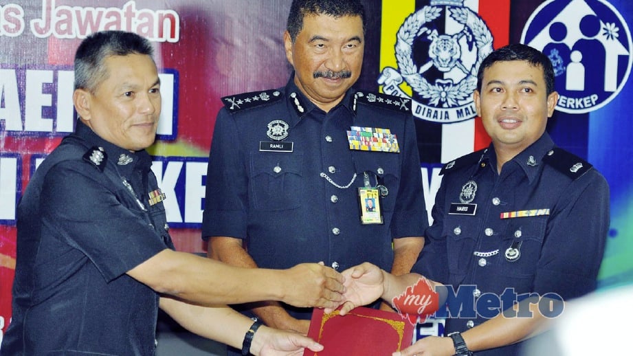 RAMLI menyaksikan Pemangku Ketua Polis Daerah Penampang, Asistan Supritenden Roni Abdul Rahim (kiri) menyerahkan nota serah terima tugas jawatan Ketua Polis Daerah Penampang kepada Haris (kanan). FOTO Mohd Adam Arinin