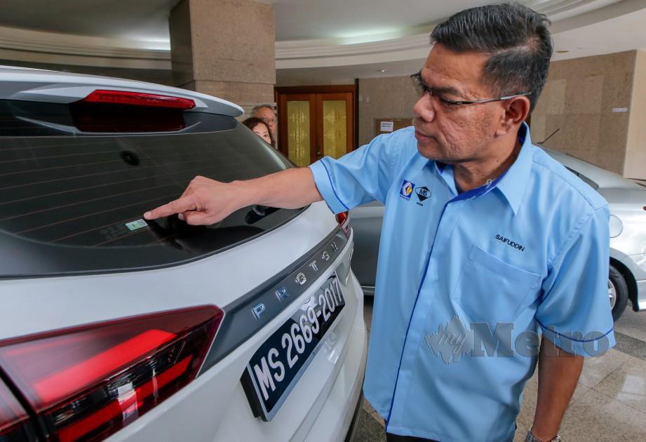 Saifuddin menunjukkan label pengesahan kod QR SIRIM pada Majlis Pelancaran Garis Panduan Pematuhan Standard Filem Penghadang Haba Kenderaan 2019. FOTO LUQMAN HAKIM ZUBIR