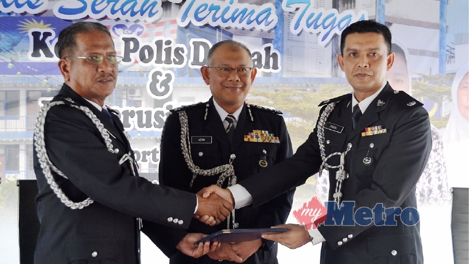 ZAINUDIN (kiri) menyerahkan Buku Serah Tugas Ketua Polis Daerah Port Dickson kepada Mohd Faisal sambil disaksikan Noor Azam (tengah). FOTO Mohd Khidir Zakaria