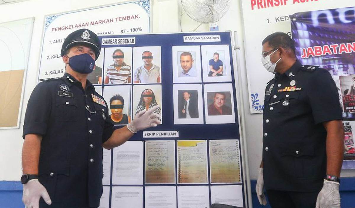 RAZALI (kiri) menunjukkan gambar saspek yang ditahan semasa serbuan dibuat dirumah saspek ketika sidang media kejayaan menumpaskan sindiket Love Scam, Parcel Scam dan pengedaran dadah melibatkan warganegara asing di IPK Melaka. FOTO Syafeeq Ahmad