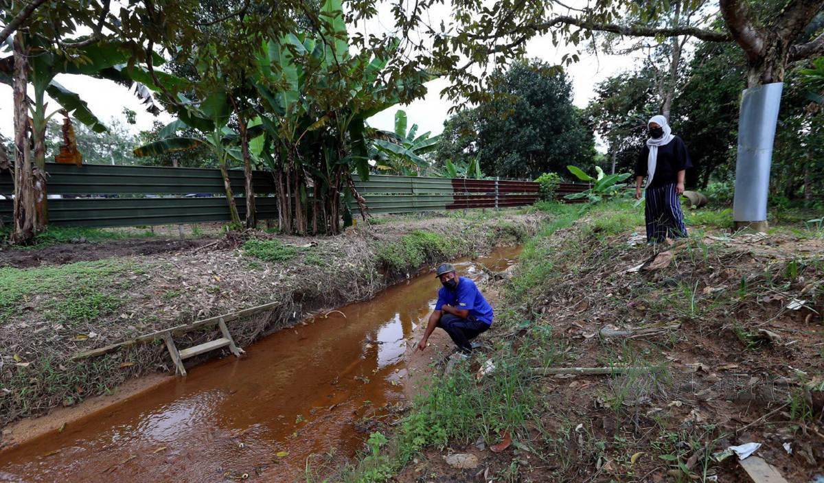 ROZINA bersama suaminya Abd Rahim menunjukkan  keadaan anak sungai selepas seminggu kejadian kes pembuangan sisa kimia industri terjadual berbahaya di Kampung Baru Sri Aman, Seelong Kempas. FOTO Nur Aisyah Mazalan