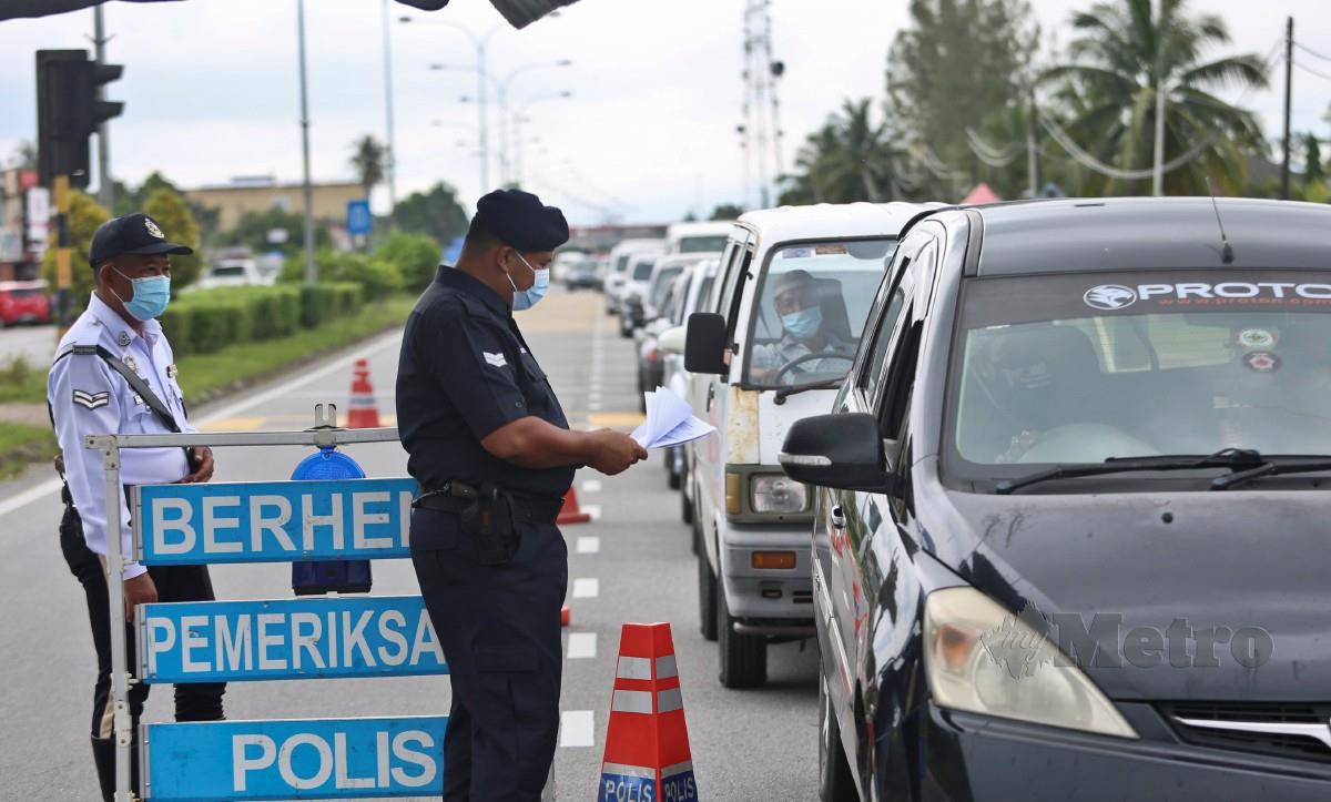 Anggota polis memeriksa dokumen perjalanan pengguna jalan raya pada sekatan jalan raya (SJR) di Jalan Padang Midin menghala ke Pusat bandar. FOTO GHAZALI KORI