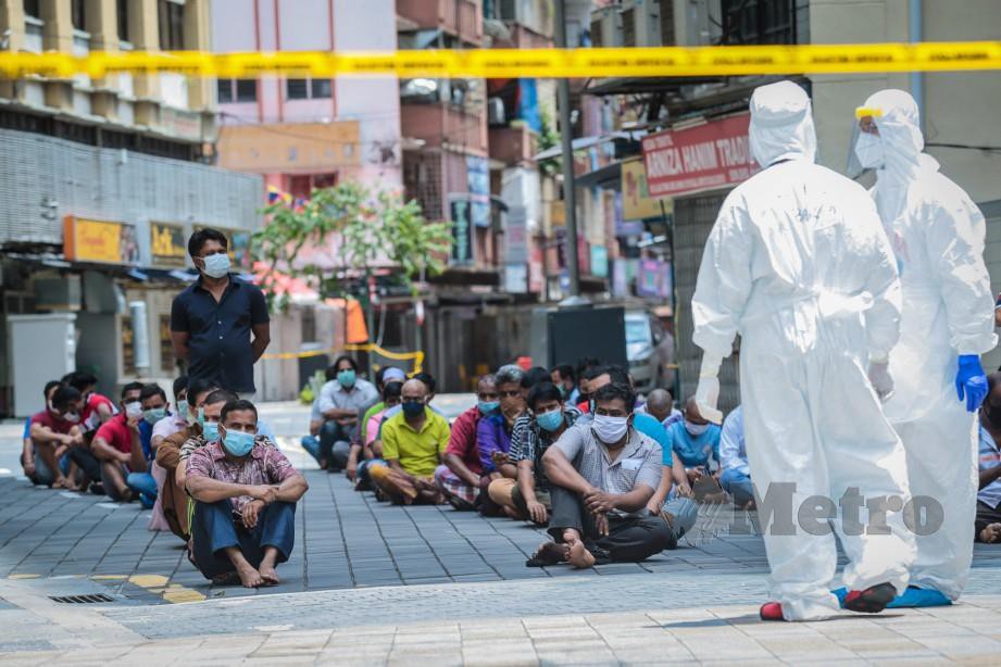 PETUGAS pelbagai agensi termasuk Kementerian Kesihatan Malaysia dan Polis Diraja Malaysia (PDRM) yang lengkap berpakaian peralatan perlindungan diri (PPE) mengumpulkan penghuni dan pekerja di sekitar kawasan Masjid India untuk menjalani saringan Covid-19. FOTO Asyraf Hamzah