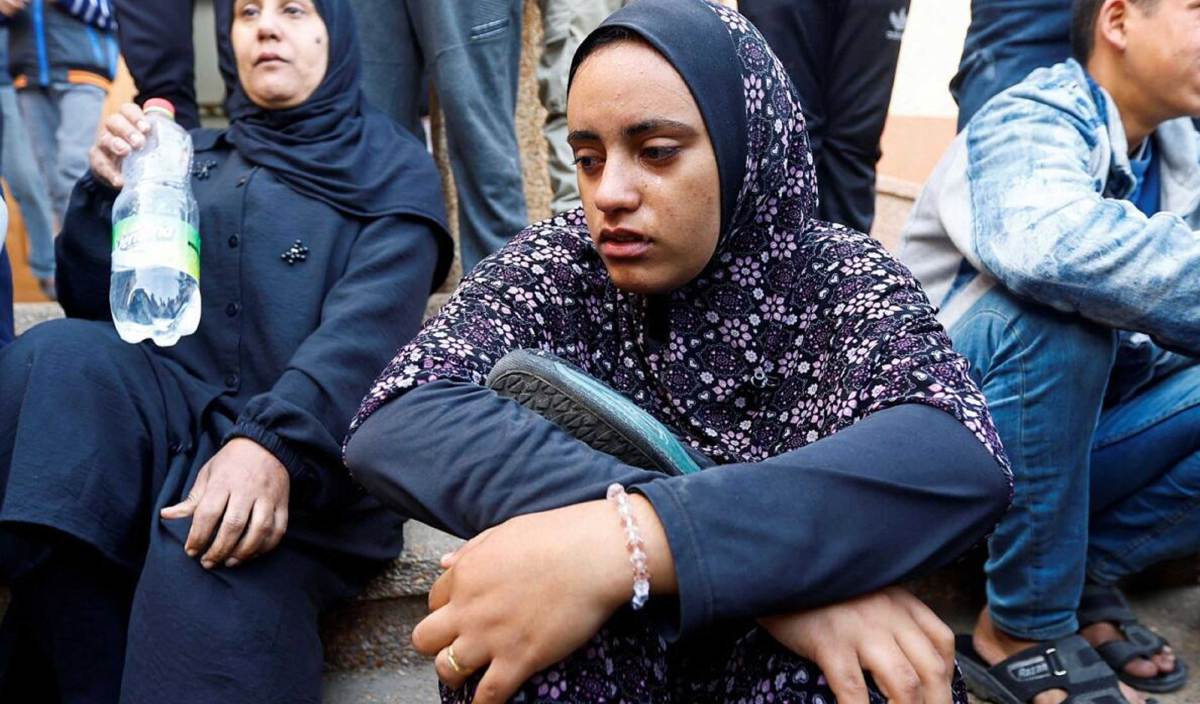 ROUZAM tidak dapat menahan sebak ketika mendakap kasut milik suaminya yang syahid. FOTO Reuters