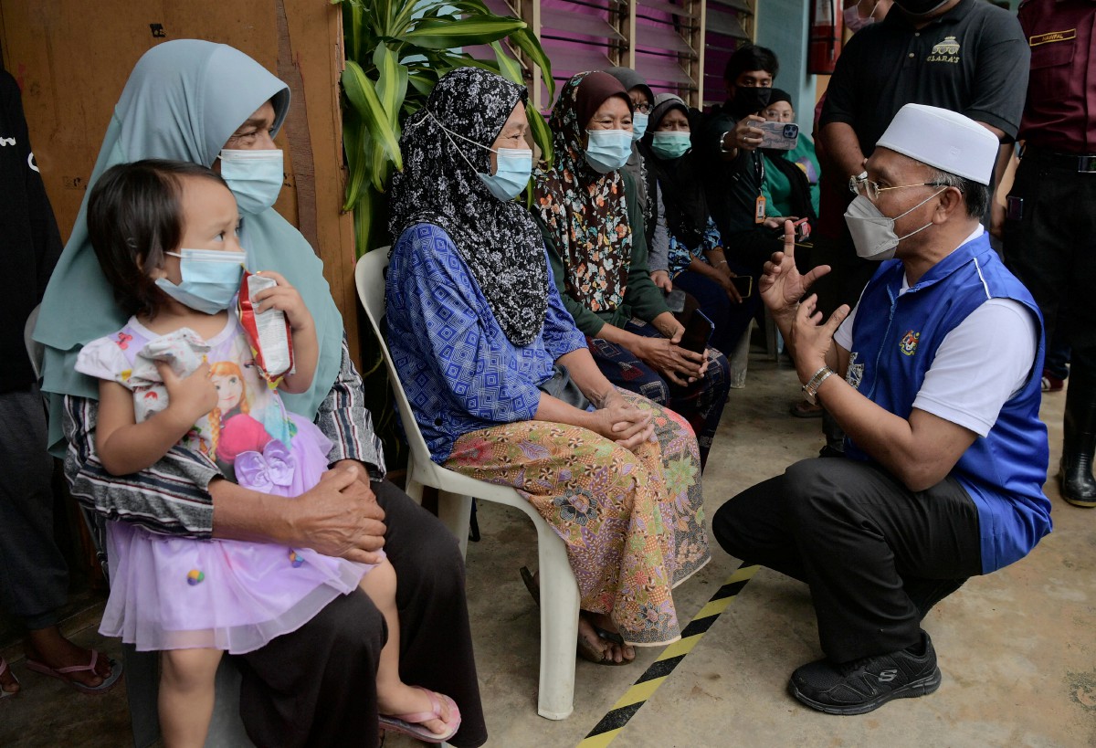 IDRIS beramah mesra dengan mangsa banjirdi pusat pemindahan sementara Sekolah Agama Kuala Paya. FOTO Bernama 