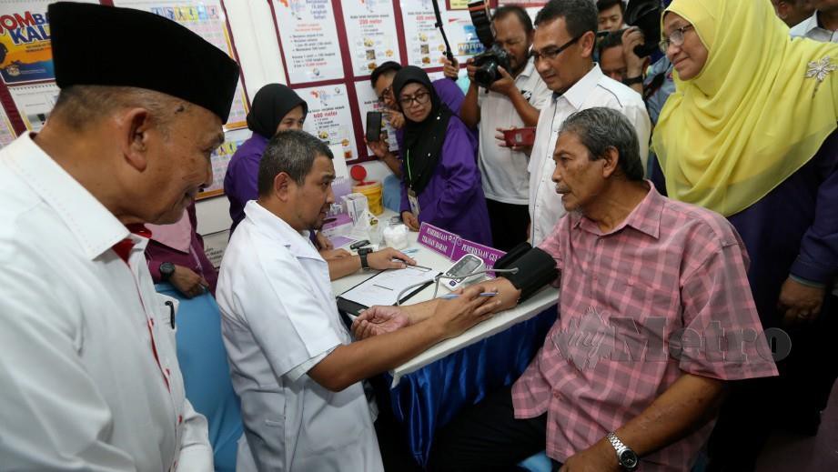 Dr Sahruddin Jamal (dua dari kiri) memeriksa tekanan darah dan gula pesakit, Zakaria Mohd Yunos (kanan), ketika majlis lawatan kerja Menteri Besar Johor di Daerah Kulai. FOTOMOHD AZREN JAMALUDIN