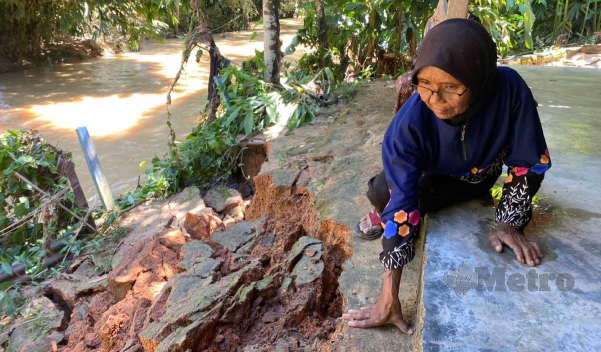 RAFEAH menunjukkan tebing sungai di tepi rumahnya di Kampung Lubuk Tualang yang runtuh. FOTO Noorazura Abdul Rahman