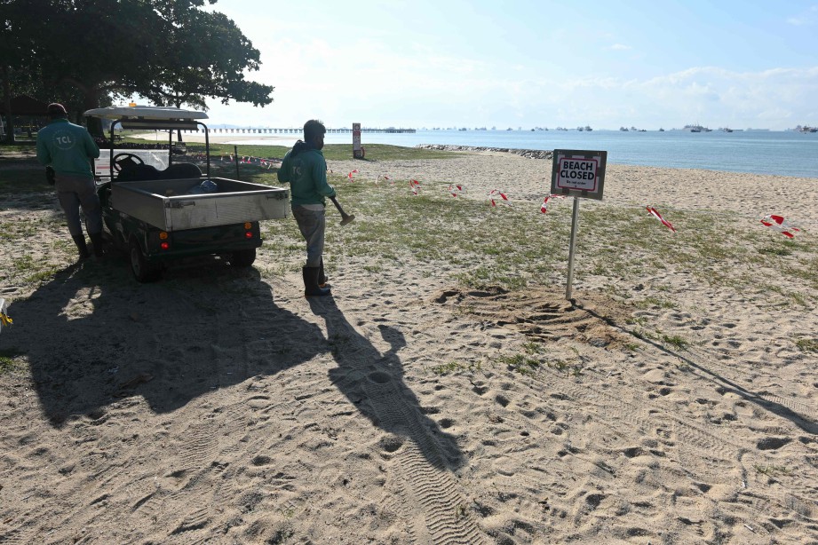 PEKERJA memasang papan tanda pantai ditutup di East Coast Park, SIngapura. FOTO AFP 
