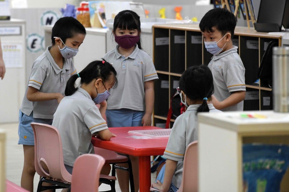 KANAK-KANAK memakai pelitup muka selepas sekolah di Singapura kembali dibuka, hari ini. FOTO AFP 