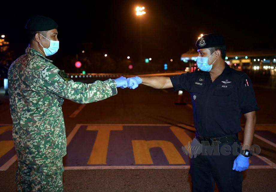 ANGGOTA PDRM bersama ATM melakukan ‘Fist Bump’ selepas selesai tugas pada sekatan jalan raya berdekatan Plaza Tol Gombak menghala ke Kuala Lumpur. FOTO Bernama 
