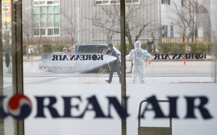 KAKITANGAN menyembur penyembur pembasmi kuman di depan ibu pejabat Korean Air di Incheon, pada 25 Februari lalu. FOTO AFP/South Korea OUT  