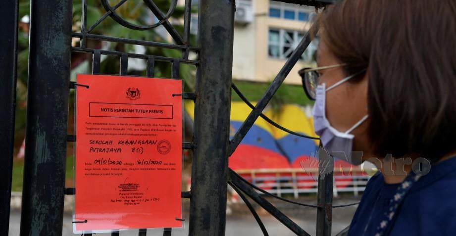Wartawan membaca notis perintah tutup premis yang di gantung di pagar Sekolah Kebangsaan Putrajaya Presint 8(1) hari ini. FOTO Bernama