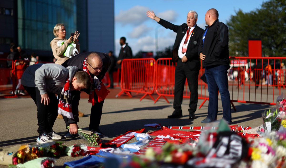 PENYOKONG meletakkan bunga di depan tugu George Best, Denis Law dan Bobby Charlton di luar Old Trafford. FOTO Reuters