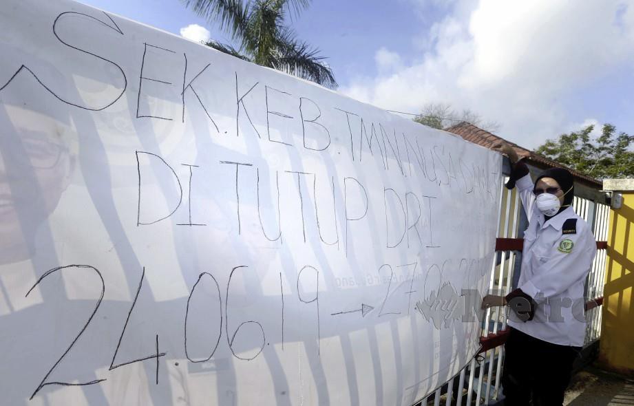 Pengawal keselamatan memasang notis pemberitahuan mengenai penutupan sekolah di pintu pagar selepas berlaku pencemaran udara di Sekolah Kebangsaan (SK) Taman Nusa Damai, Pasir Gudang. Foto Hairul Anuar Rahim 