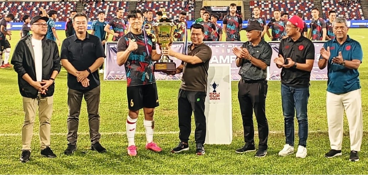 KASSIM (tengah) menyampaikan piala kepada kapten Sabah FC, Park Taesu selepas perlawanan akhir menentang KL City di Stadium Likas. FOTO Ihsan Sabah FC