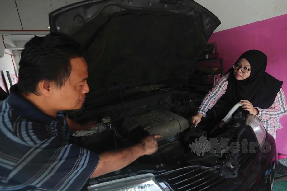 BERSAMA suami memeriksa kenderaan pelanggan. FOTO Muhammad Asyraf & Saudah Salleh